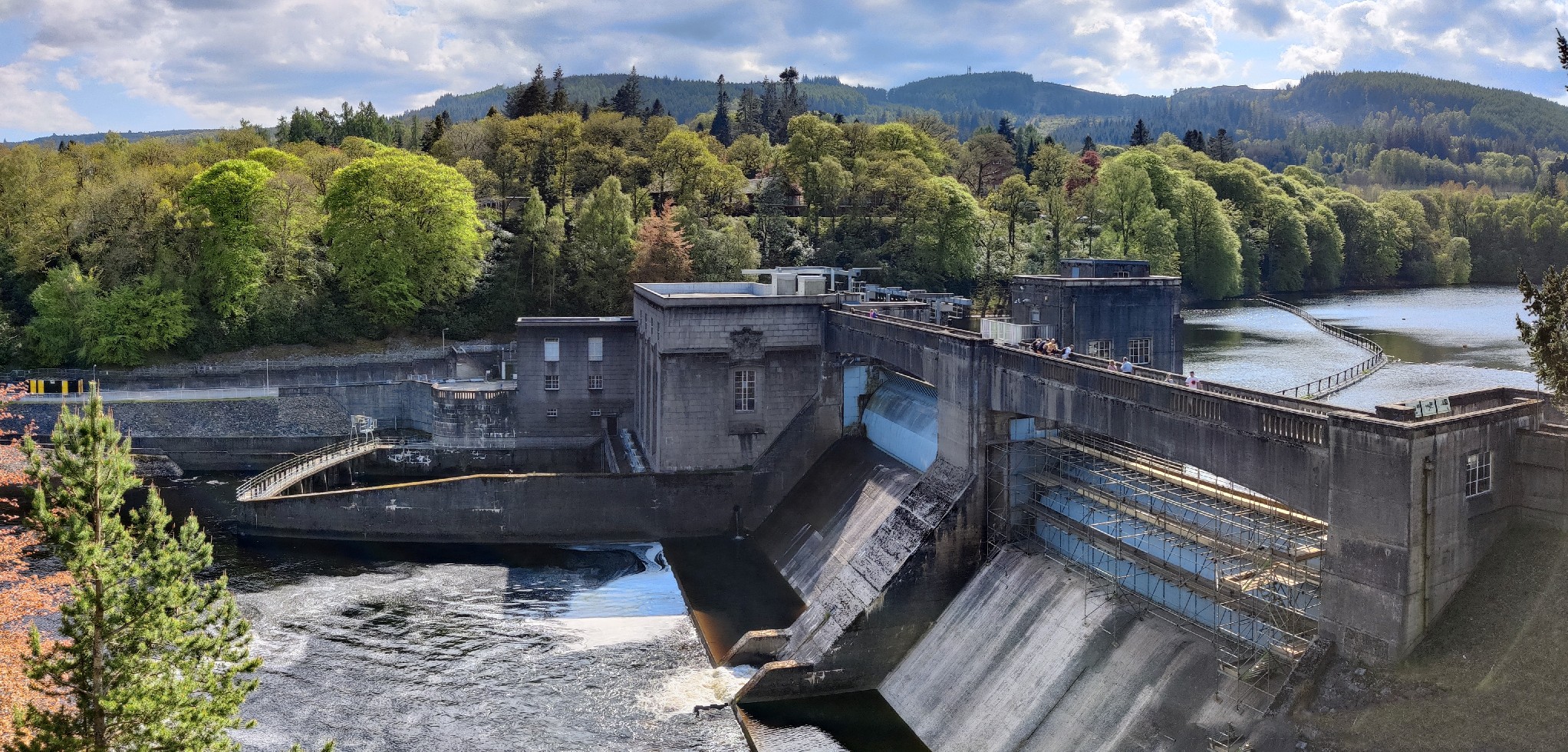 A concrete dam, water is gushing out from the main channel, but the water level is not particularly high.