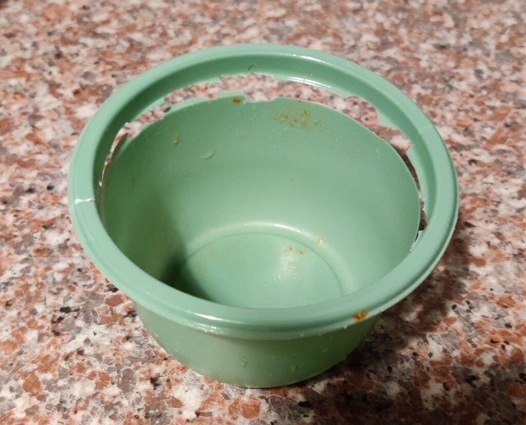 A broken plastic dish, the rim is cracked and detached from the bowl