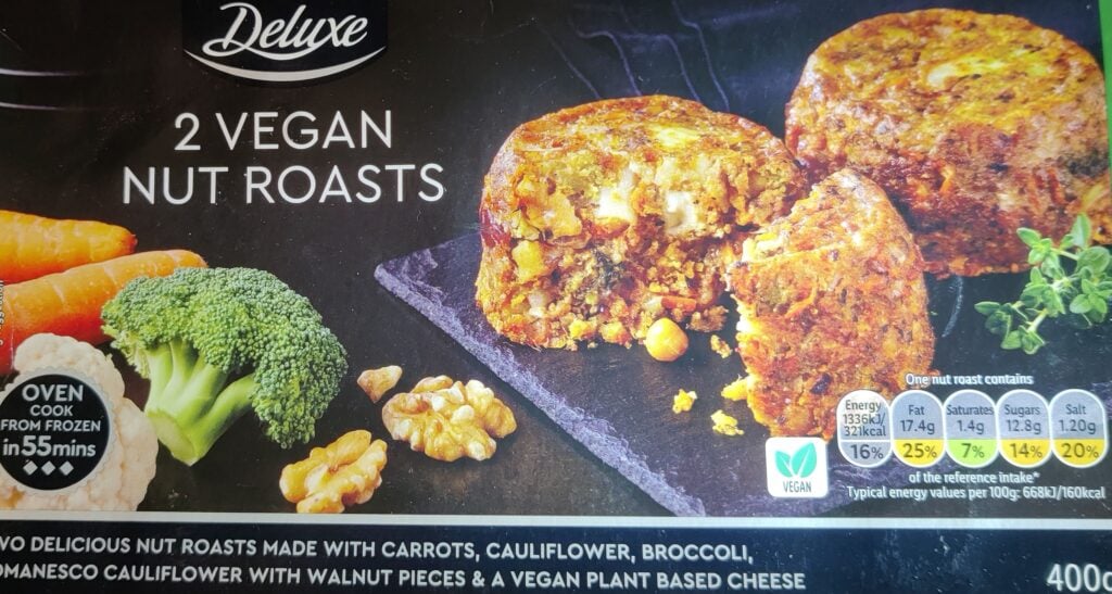 a package of 2 vegan nut roasts, golden and crumbly with some brocolli and nuts to the side